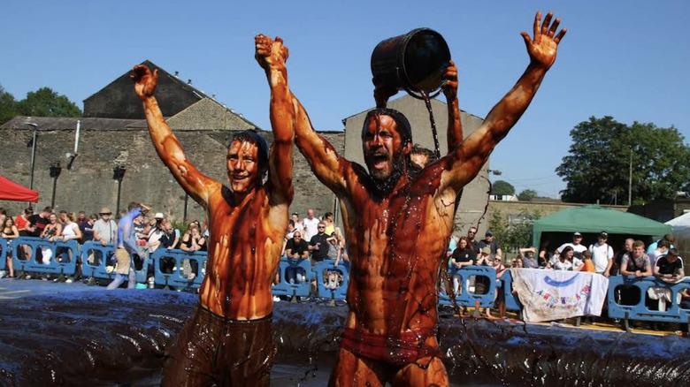 A man dumps a bucket of gravy on a  competitor at the World Gravy Wrestling championship.