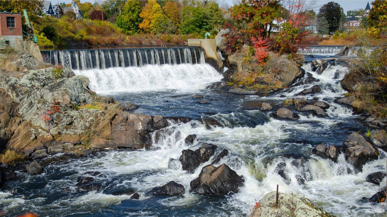 Putnam, Connecticut, with a river, a waterfall, and fall colors against a blue-gray sky with rocks and buildings