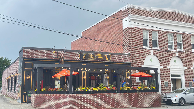 The Hare & The Hound Restaurant, a brick, white, and black Irish pub near Putnam's Main Street, with a gray sky
