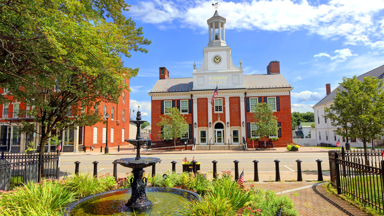 Westborough Town Hall with a clock tower and old-world architecture seen behind a water fountain in a Westborough park