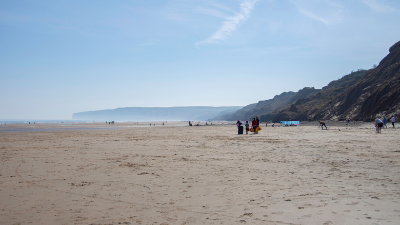 The wide long beach at Hunmanby Gap with a few beachgoers and misty cliffs in the distance
