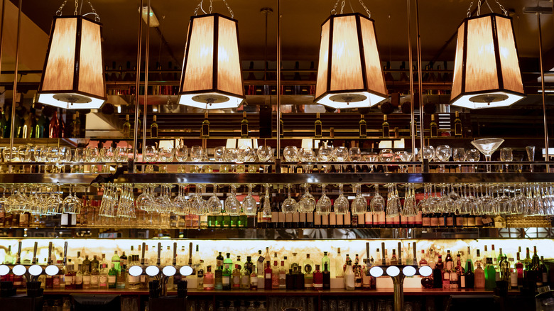 Image of a British pub's bar with glasses and alcohol lining the wall and counter