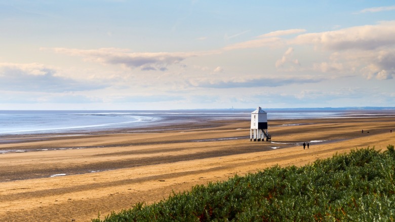 A wooden lighthouse on a sprawling sandy beach in Burnham-on-Sea, England