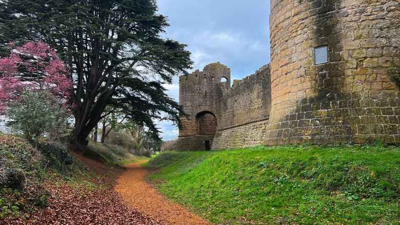 A tree-fringed walking path passing the remains of medieval towers and walls at Caldicot Castle and Country Park