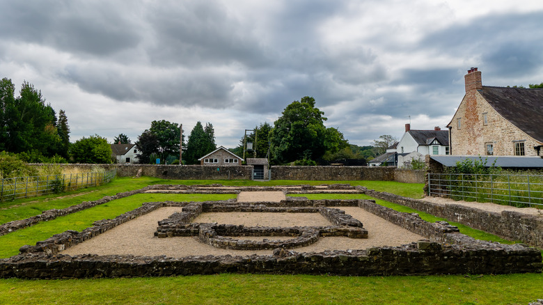 The low-lying ruins of the walls of a Roman temple in the village of Caerwent with nearby houses
