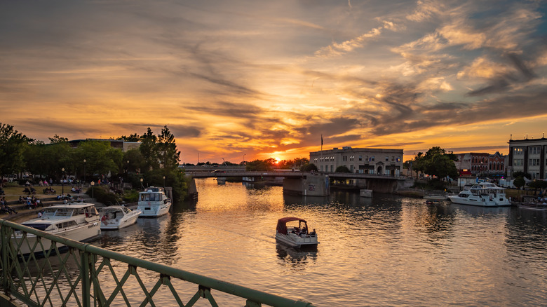 sunset over river with boat on it