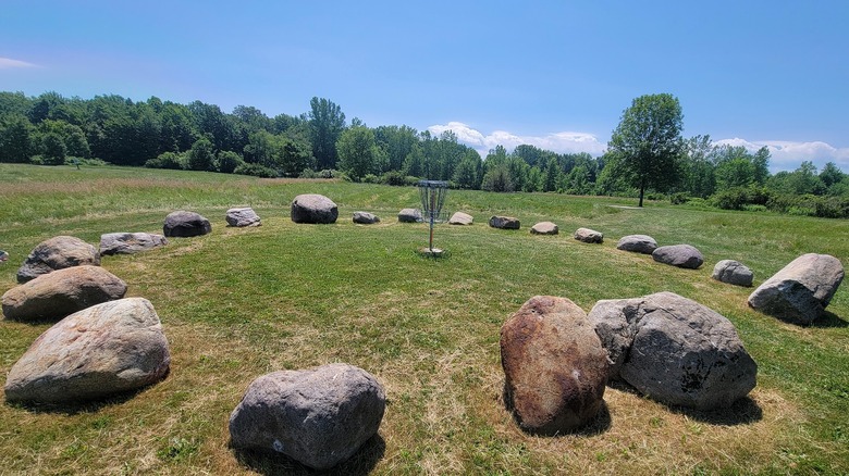 A disc golf basket surrounded by large stones.