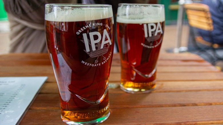 A close up of two pints of Greene King IPA on a wooden table