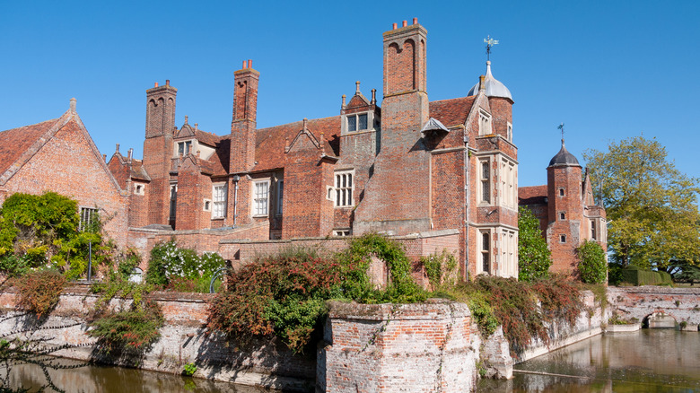 The historic Kentwell Hall with redbrick Tudor architecture surrounded by a moat in Long Melford