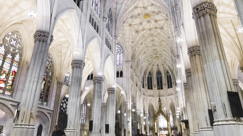 The interior of St. Patrick's Cathedral in New York City with stained glass windows and stone pillars
