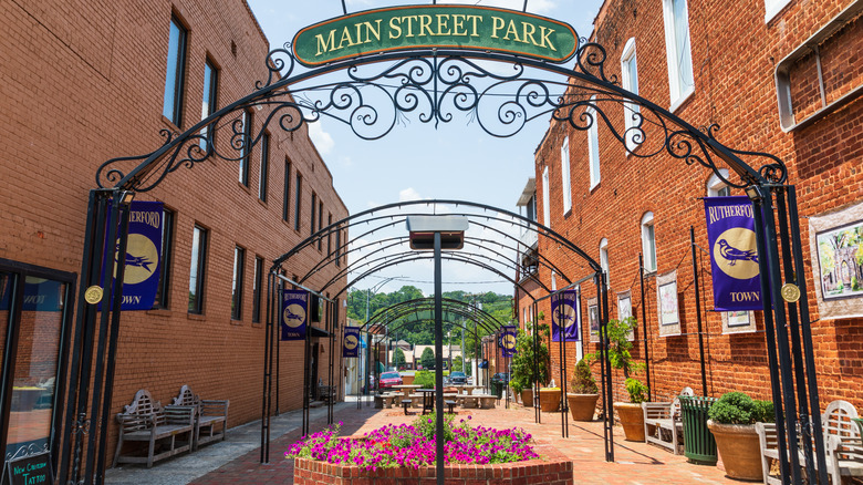 A colorful urban park with flowers and greenery is bounded by two brick buildings in Rutherfordton, NC