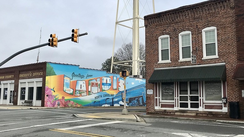 An intersection in Landis, North Carolina, with a bright mural possessing the town's name and store fronts.