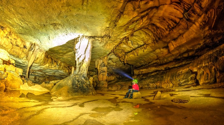 Person sits inside Tumbling Rock Cave and shines headlight on rock formation