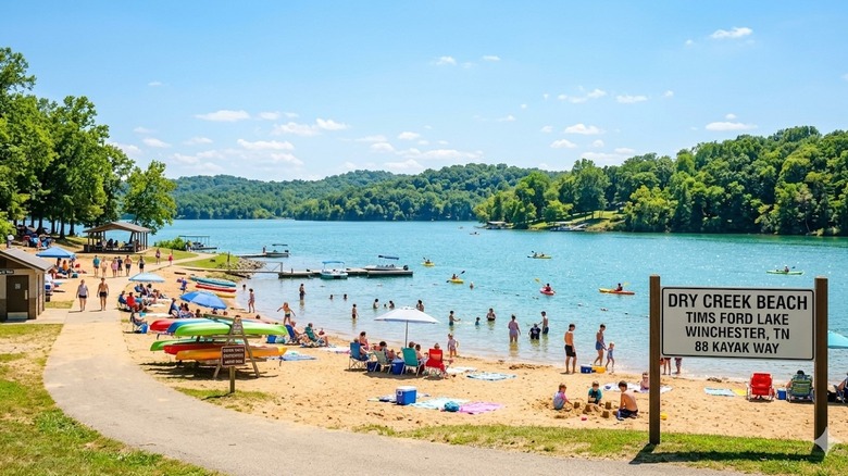 A crowded public beach near Estill Springs, Tennessee, featuring a sandy shore, clear blue waters, and greenery.