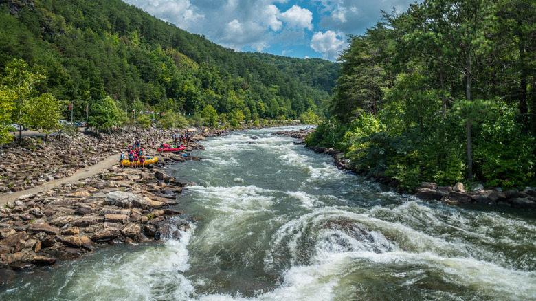 Swirling rapids of Ocoee River framed by lush trees and rafters waiting to go in