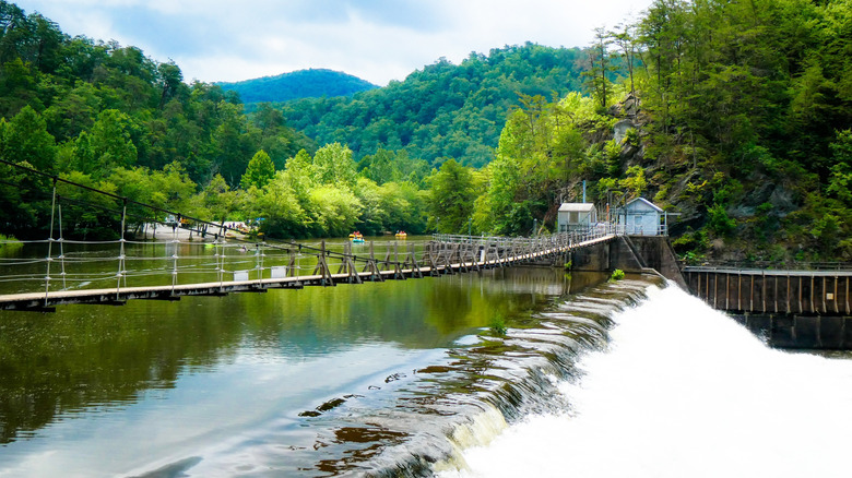 Dam opens with rushing water and kayakers, surrounded by trees, on the Ocoee River in Tennessee