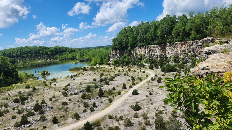 closer view of the quarry cliff and a hiking trail with the pond in the background