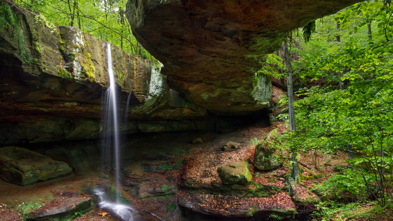Rockbridge from below with waterfall cascading next to green plants