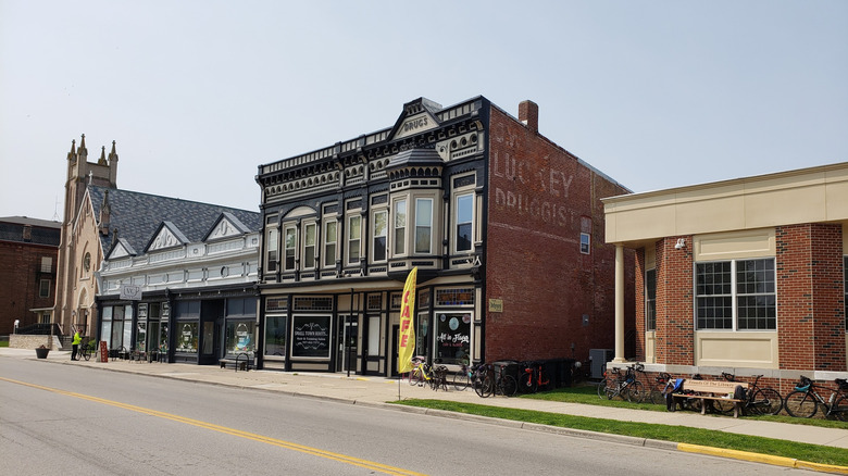 Street in South Charleston, Ohio, with a church and brick buildings with painted storefronts and bicycles out front, under a blue sky