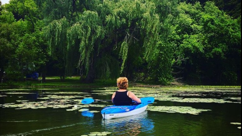 A kayaker paddling between lily pads on Leesville Lake, OH.