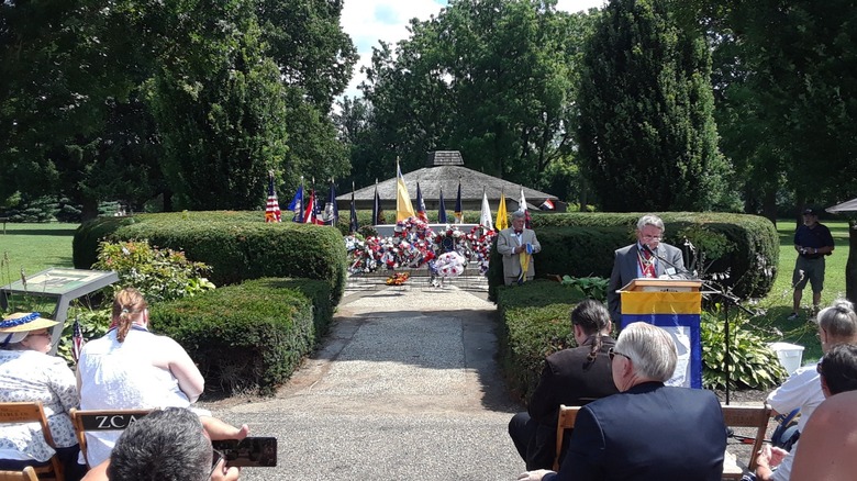 A group of onlookers pays respect at the Tomb of the Unknown Patriot at Fort Laurens.