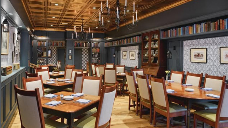 interior of Golden Lamb's Dickens Room, wooden dining tables and chairs, candle chandeliers