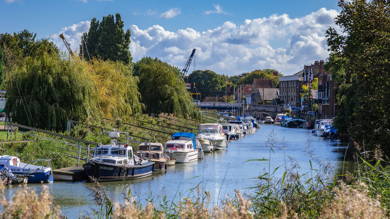 Boats and buildings lining the Stour river against a cloudy sky in Sandwich, U.K.