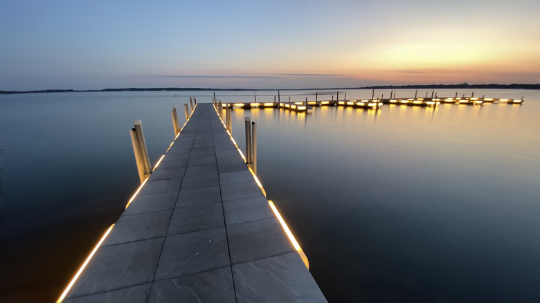 Dock lit up at sunset on calm lake