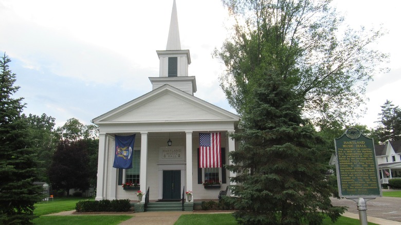 The white Hartland Music Hall, with four pillars and a steeple