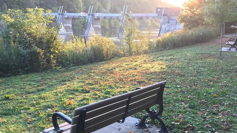 Bench overlooks dam on Thames River inside Springbank Park