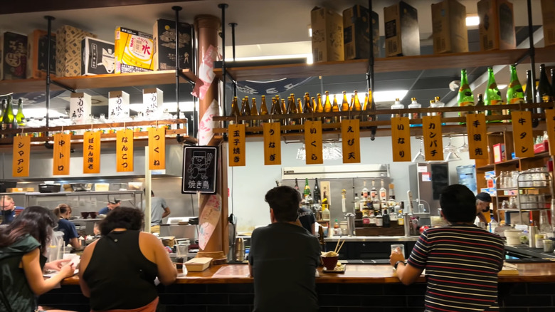 People sitting at the bar in a traditional Japapnese izakaya called Susuru, in Orlando, Florida.