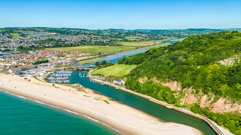 Aerial shot of Seaton capturing its beaches, river, harbor, cliffs, houses, and distant wetlands