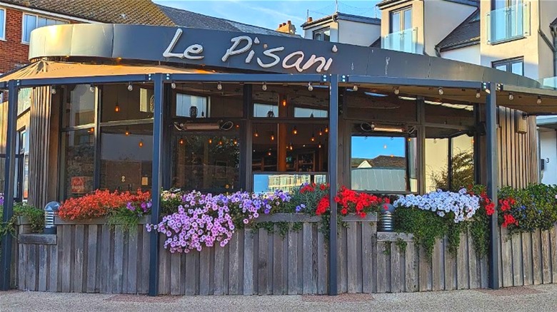 The exterior of Le Pisani, a Mediterranean restaurant in Seaton with flowers and glass walls