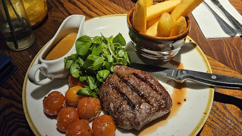Plated grilled steak with salad and handcut chips with gravy at the Fettykil Fox