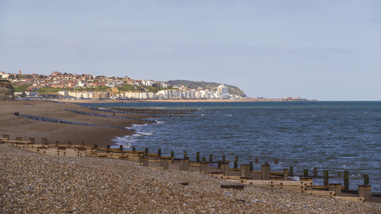An empty, pebbly beach with white buildings on the horizon in Bexhill-on-Sea, England