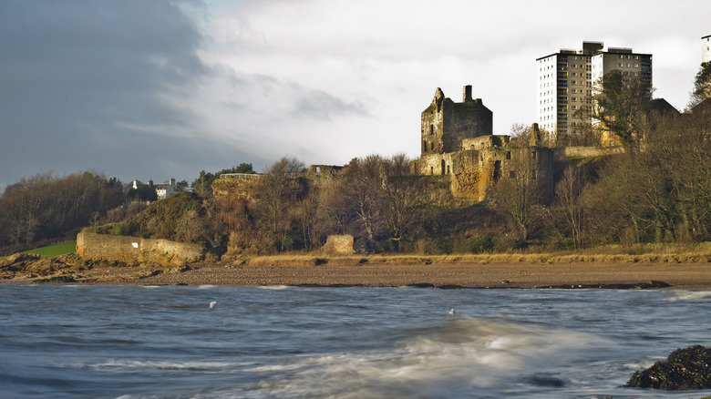 The 15th century Ravenscraig Castle on a hill above a small beach in Kirkcaldy, with bare trees of the colder seasons and grey skies