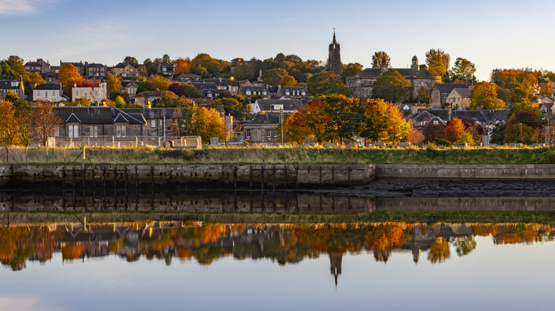 A still lake reflects the trees and houses around it in fall in Bo'ness, Scotland