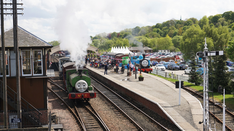 Green and blue steam trains with smiley faces resemble characters from the children's TV show 