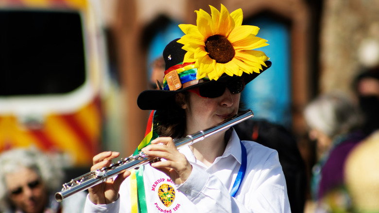 A woman playing a flute and wearing a sunflower on her hat during Sidmouth Folk Festival