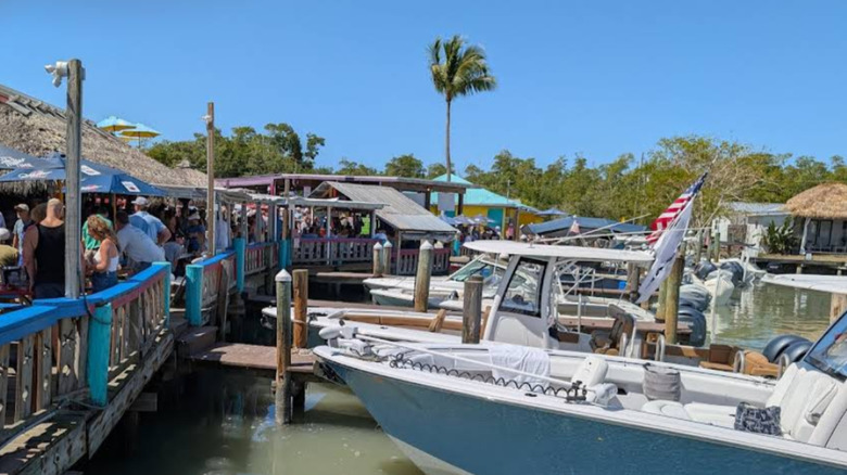 A view of a busy restaurant along the dock in Goodland, Florida, with boats pulled right up to the restaurant patio