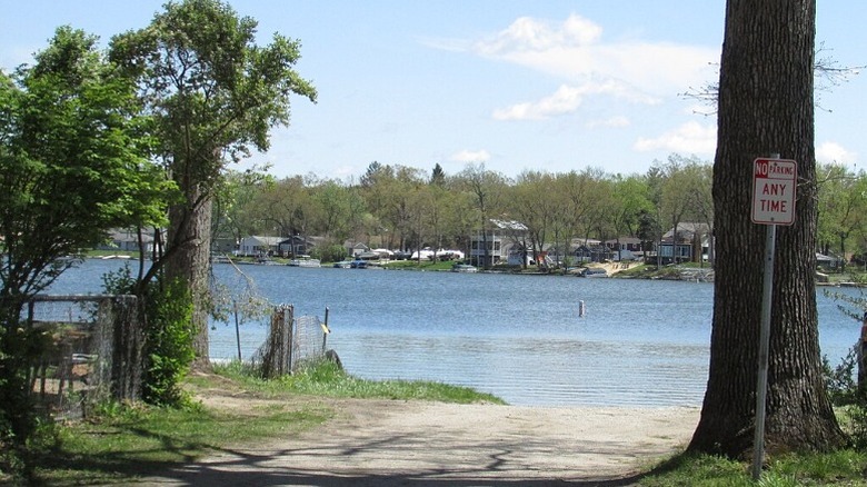A boat launch on the water at Koontz Lake with trees and houses on the opposite shore.