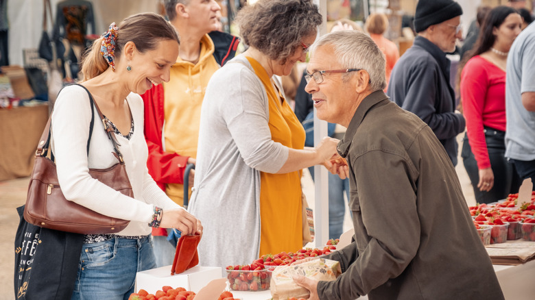 A woman buying strawberries from a farmer