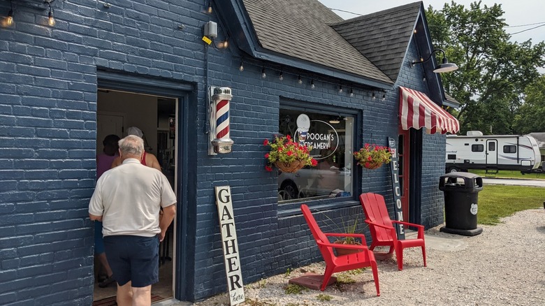 Blue painted brick exterior Poogan's Creamery with red chairs and man walking inside