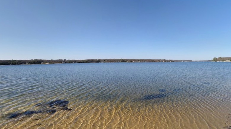 A photo from the shore of Big Star Lake showing the clear water in the shallows and a line of trees on the distant shore