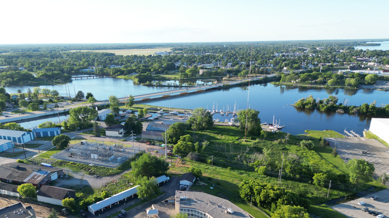 An aerial photo of the Menominee River with a bridge crossing into Michigan, small islands, sail boats at docks, a few city streets, and green trees everywhere