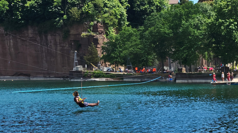 Man hanging from a zipline over the water at Brownstone Adventure Sports Park, Connecticut