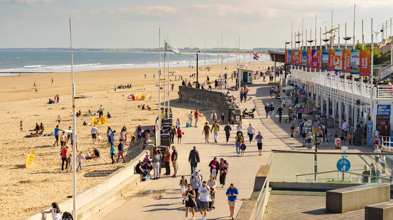 Bridlington beach and sea front on a sunny day with groups of people walking along the promenade or on the sand
