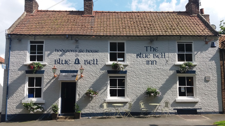 The white-brick facade Blue Bell Inn with tables, flowers, and antique sconces in Nafferton