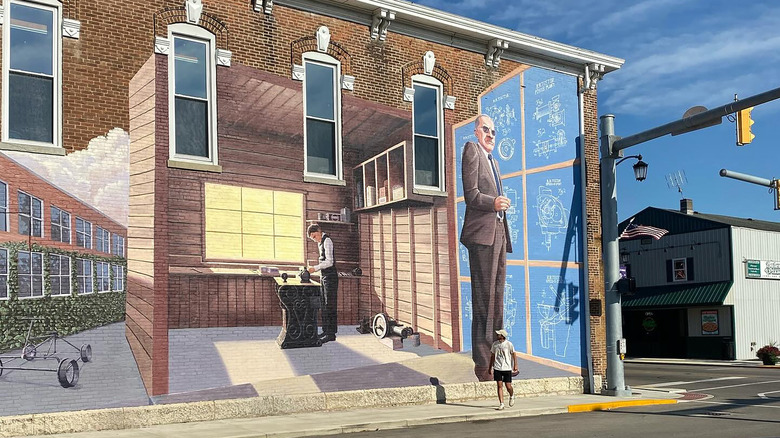 Person walking on sidewalk in downtown Hagerstown, Indiana, with mural painted on brick building in the background