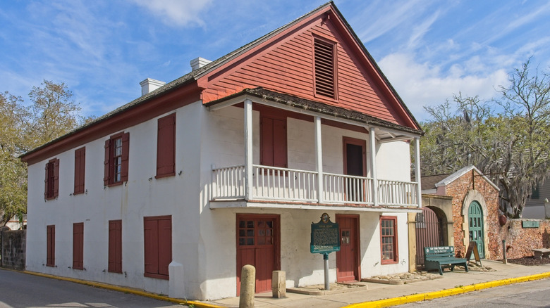 Two story white and red building, road, trees and sky in the background